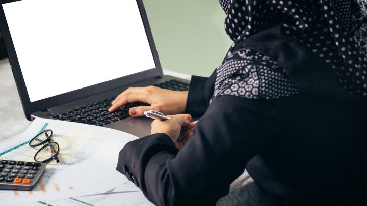 The backside of business muslim woman working on blank laptop display for editing.